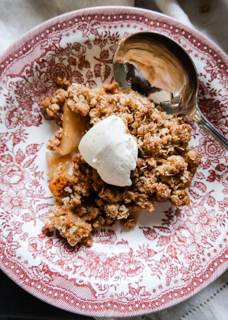 A bowl of warm apple crumble with oats in the topping