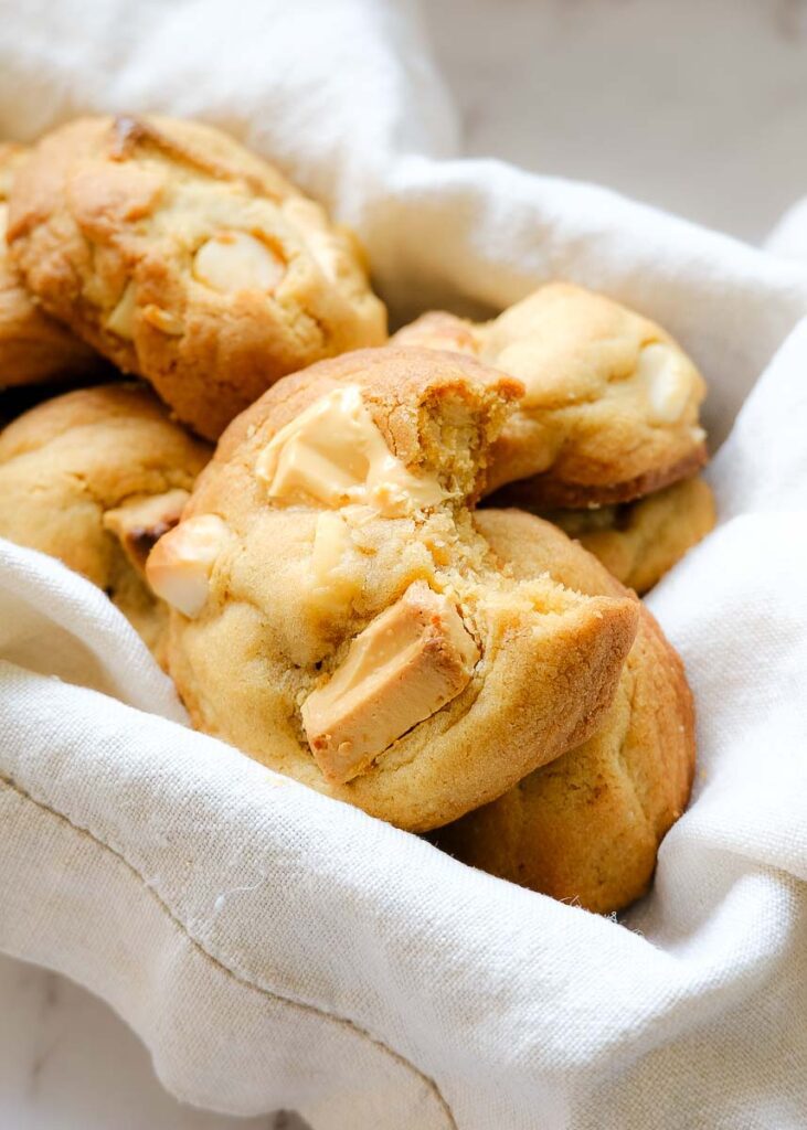 White chocolate macadamia nut cookies in an old metal baking tin lined with a linen cloth