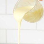 Condensed milk being poured out from a crystal milk jug