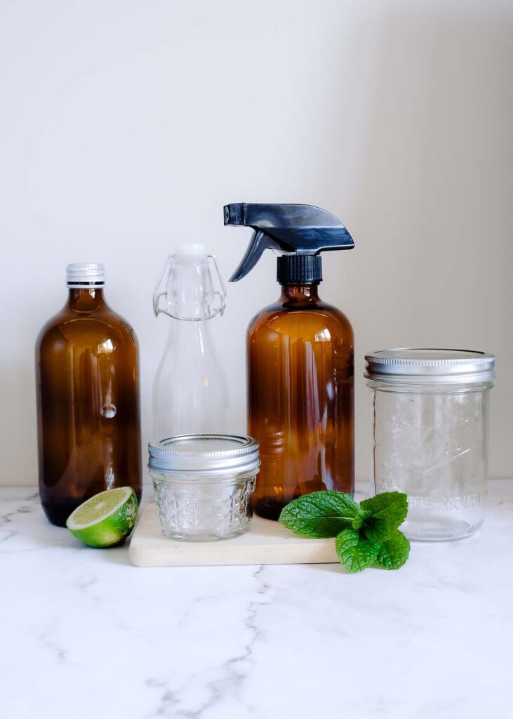 5 glass bottles and jars on a wooden board with mint and lime
