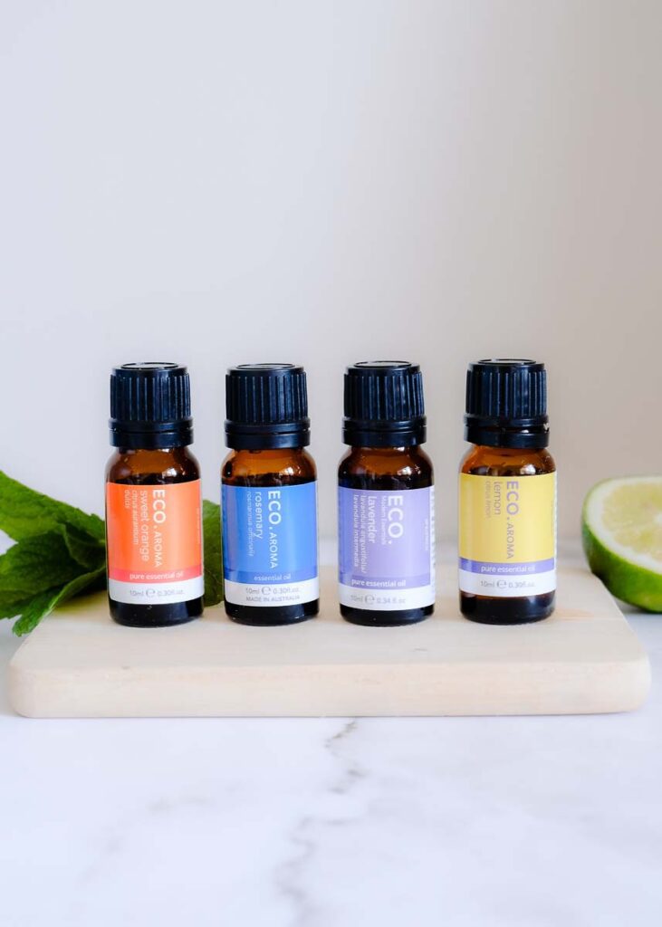 Four essential oil bottles in a row, orange, rosemary, lavender and lemon