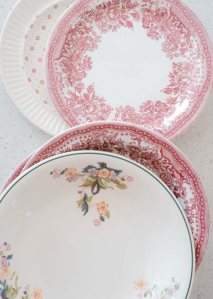 Close up of floral plates and bowls. Red with rose florals and white with dinty pastel coloured flowers