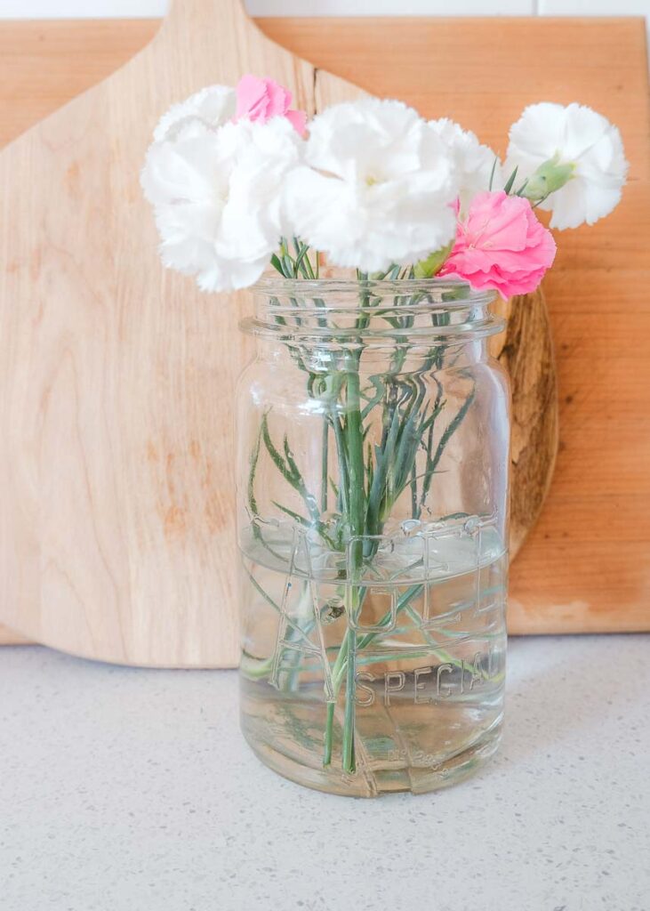 Vintage agee jar being used as a flower jar for pink and white blooms
