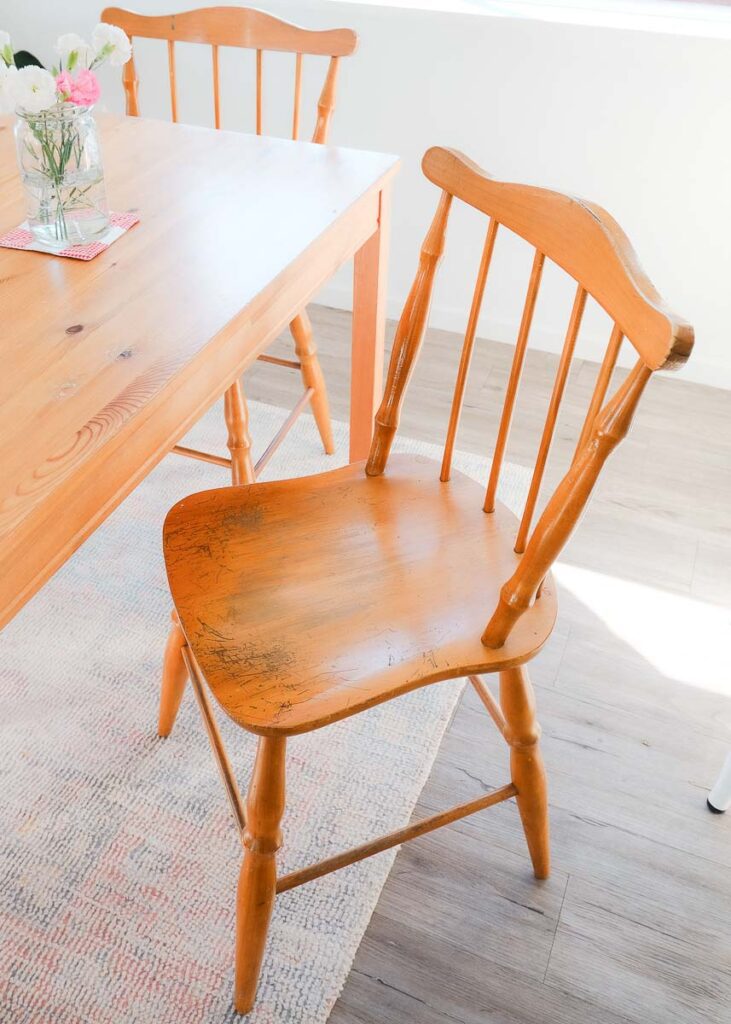 Thrifted wooden dining room chair in light wood next to dining room table in cottage kitchen