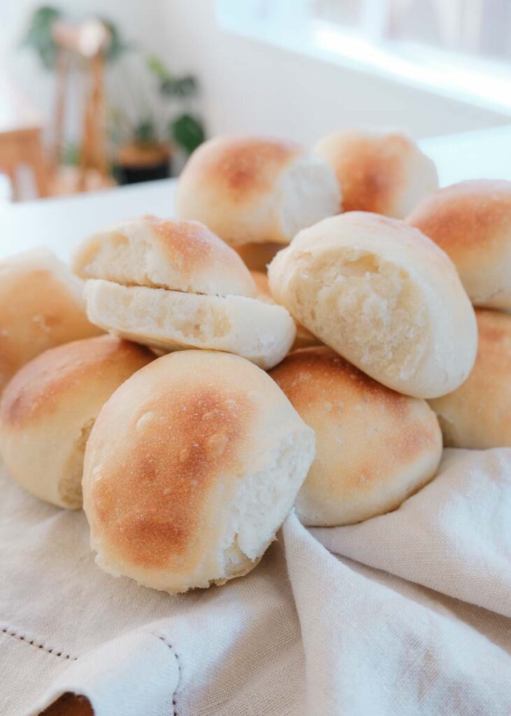 Stack of dinner rolls on a linen tea towel showing how yummy and fresh they are