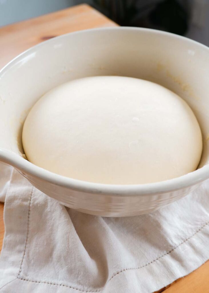 The dough has doubled in size after rising in a large ceramic bowl