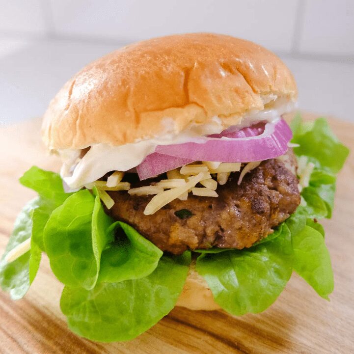 Homemade burger patty on a burger bun with salad and mayo