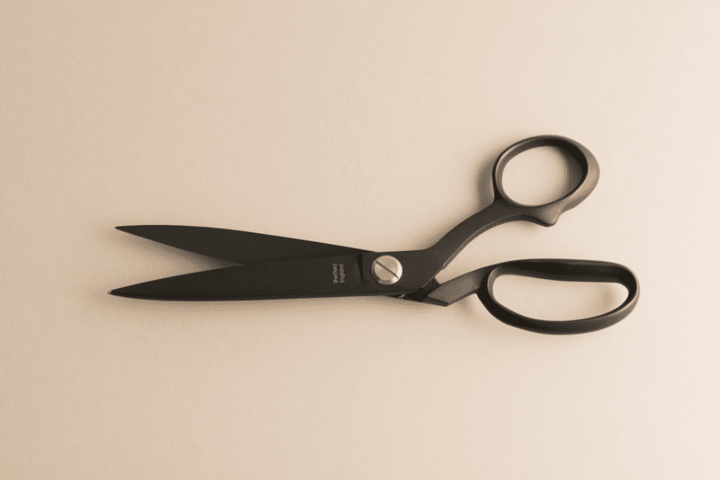 Pair of black fabric shears on a pink desk