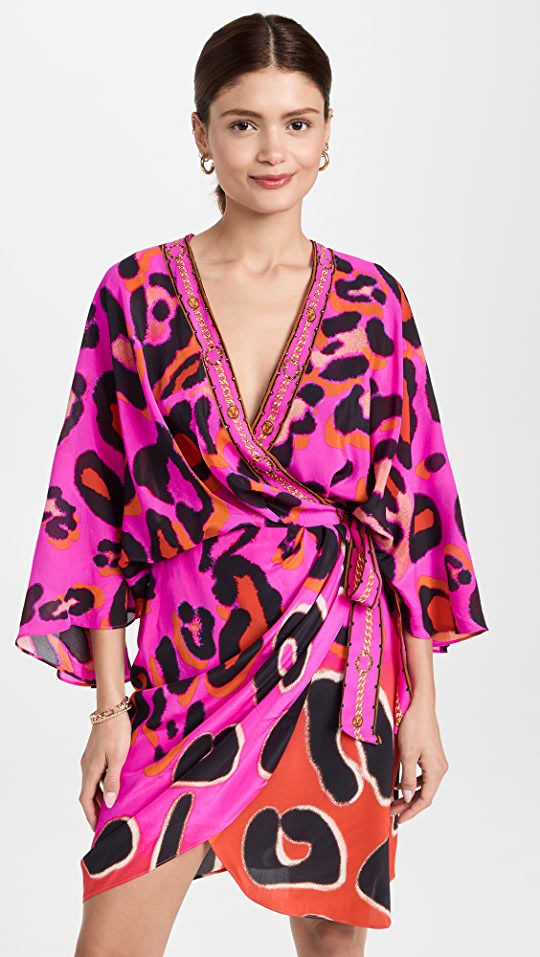 Woman wearing a batwing wrap around dress in a bright fuchsia pink with animal print