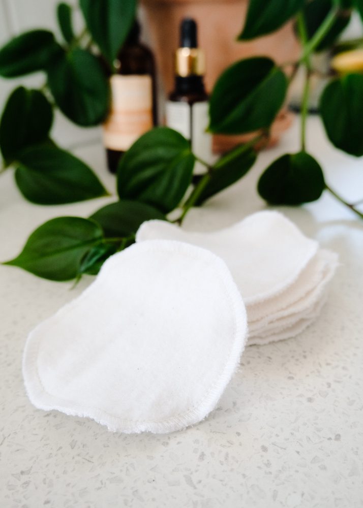 Handmade diy reusable cotton makeup pads sitting in a pile in front of greenery