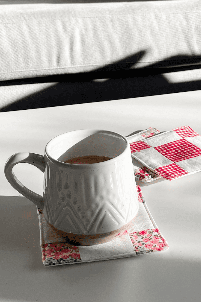 A patchwork coaster with a mug on top made following Makyla Creates free diy fabric coaster sewing project