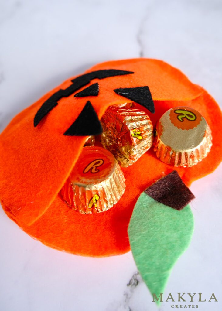 Close up of felt pumpkin treat bag filled with chocolate for Halloween