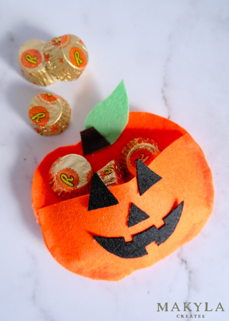 Felt pumpkin treat bag with pocket filled with Reeces pieces 