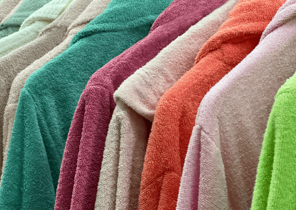 Terry cloth bathrobes in different colours hanging up