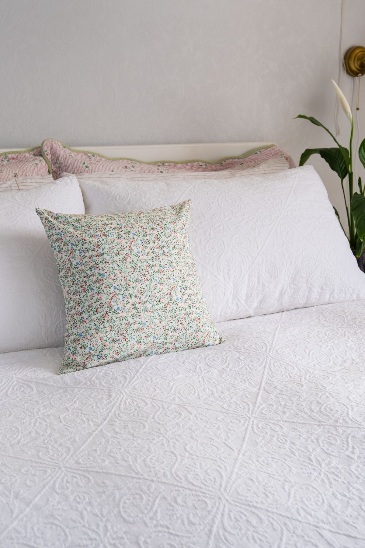 A floral envelope cushion cover on a white bed