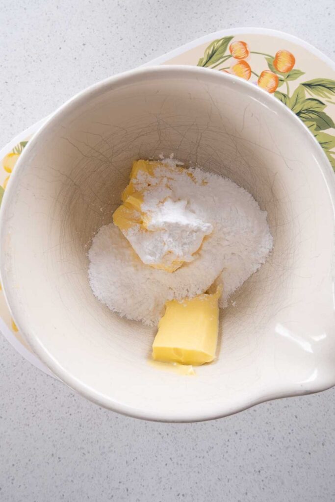 Adding icing sugar and butter into a mixing bowl