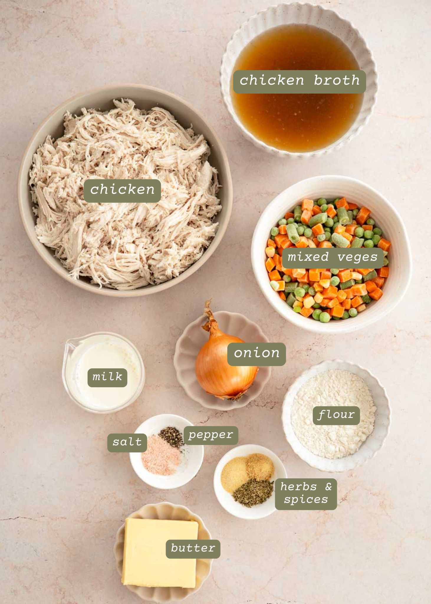 Overhead view of ingredients for Easy Chicken Pot Pie with Biscuits, including shredded chicken, chicken broth, frozen mixed vegetables, diced onion, milk, flour, butter, salt, pepper, and herbs and spices.