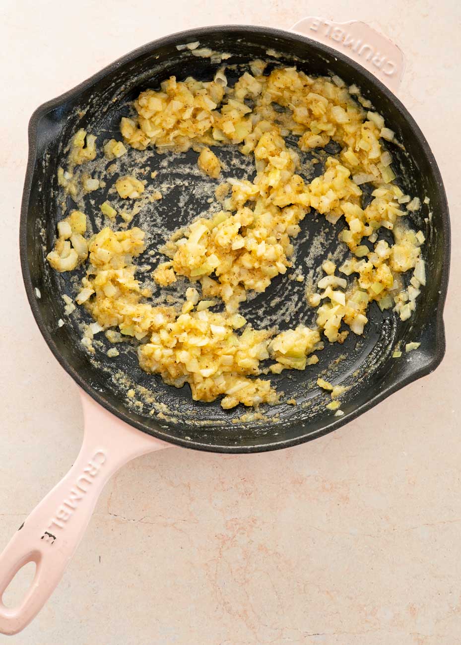 Onions, butter, and seasonings cooking together in a skillet to start the creamy pot pie sauce.