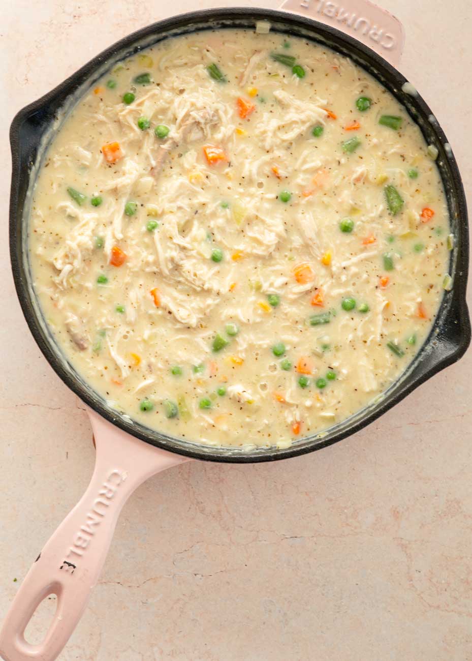 Shredded chicken and mixed vegetables stirred into the creamy sauce in the skillet.
