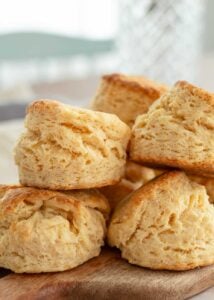 Stack of fluffy, golden old-fashioned buttermilk biscuits on a wooden board.