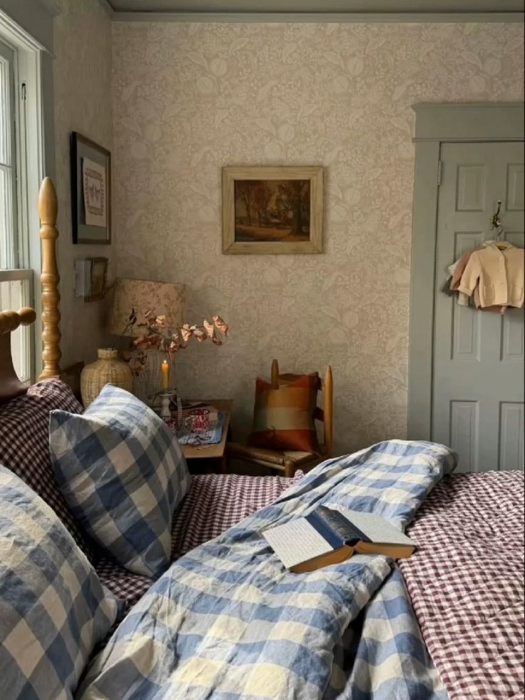 Cottagecore bedroom with large-scale blue gingham duvet and red check sheets, William Morris strawberry print wallpaper, wooden furniture, and a rattan bedside lamp