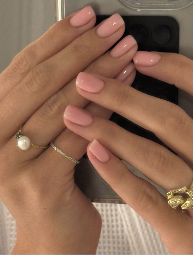 Short square nails in a soft peachy pink gel polish with a glossy finish
