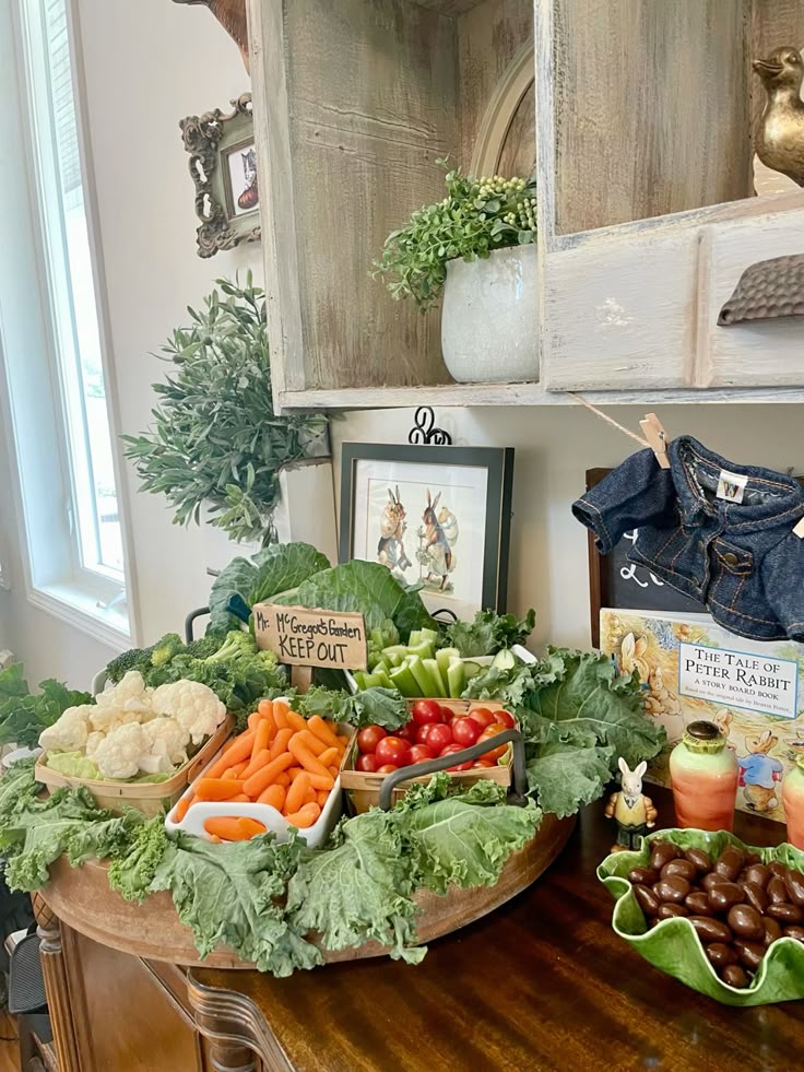 Peter Rabbit baby shower dough bowl grazing platter with kale leaves carrots cauliflower cherry tomatoes and a Mr McGregor's Garden Keep Out sign with the book nearby