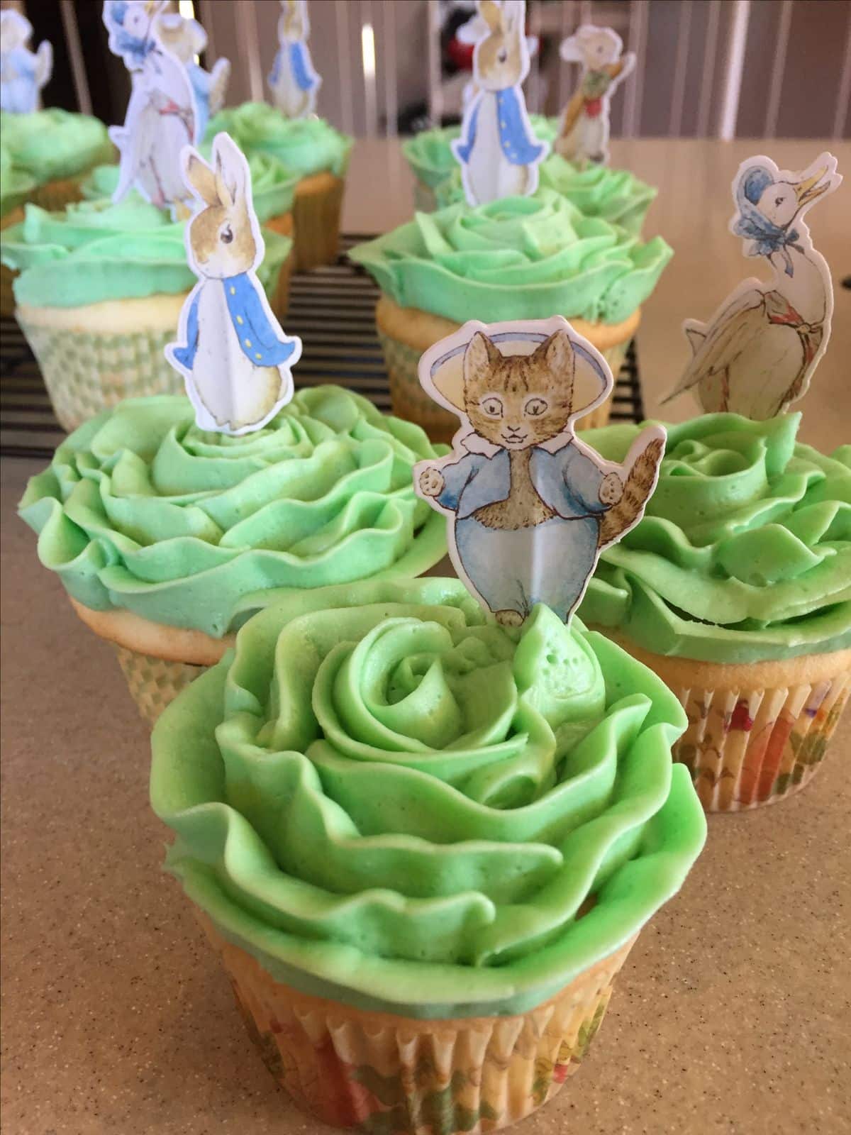 Peter Rabbit baby shower cupcakes with green rose swirl buttercream frosting and Beatrix Potter character paper toppers including Peter Rabbit Jemima Puddle-Duck and Tom Kitten