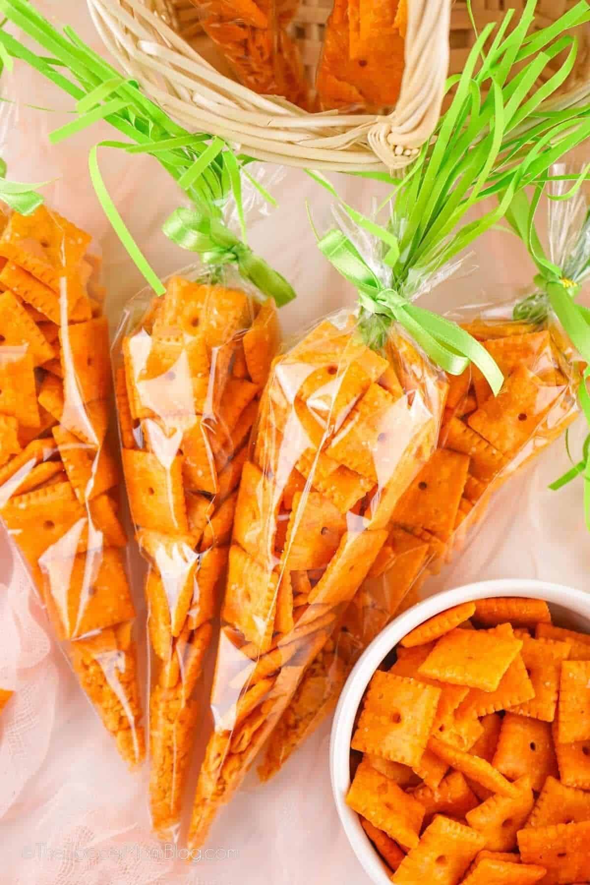 Peter Rabbit baby shower carrot shaped treat bags filled with orange cheese crackers tied with green ribbon bows to look like carrots in a wicker basket