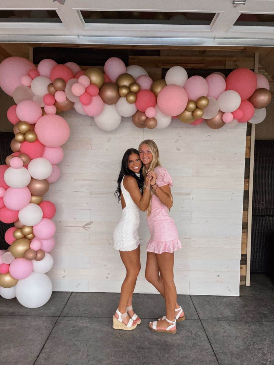 Light wood shiplap panel backdrop with a lush organic balloon garland in shades of pink mauve blush white and rose gold wrapping over the top and down one side