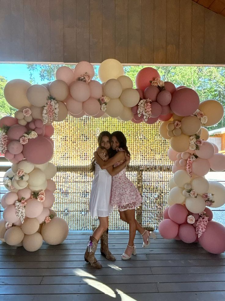 Large circular balloon arch ring in muted dusty pinks mauve blush and cream with small clusters of flowers tucked in at intervals around the ring