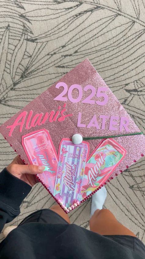 Pink glitter graduation cap with Alani Nu energy drink cans and the words 2025 later in pink lettering, decorated with pearl beads.