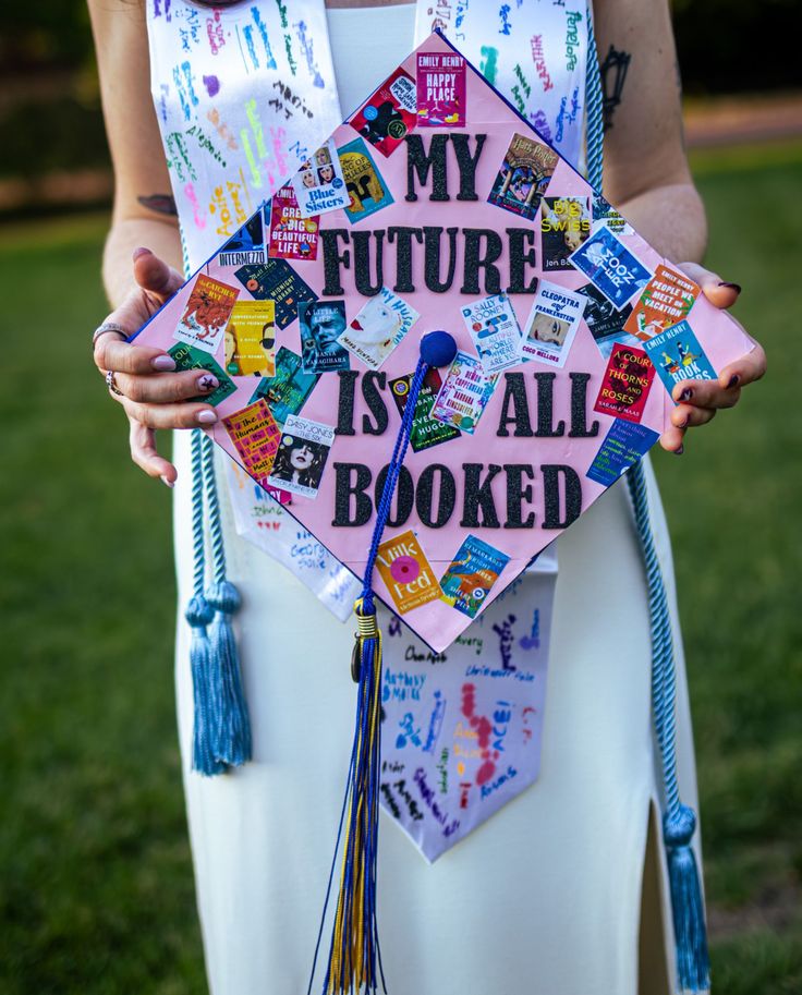 Pink graduation cap covered in miniature book cover stickers with the words my future is all booked in black glitter lettering in the centre.