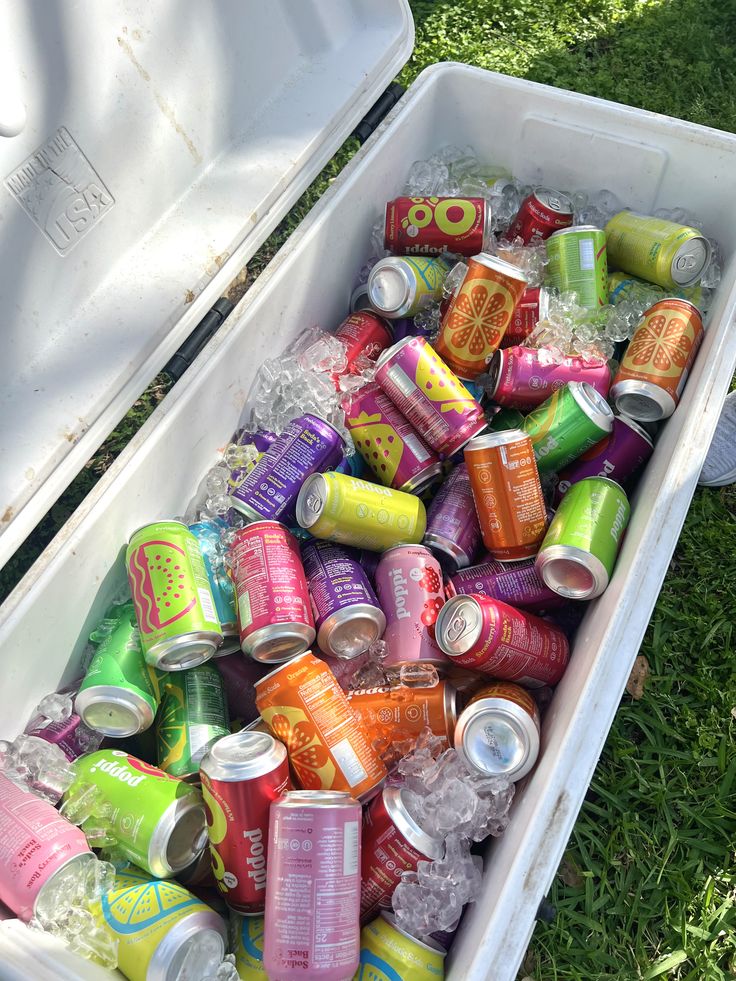 Cooler filled with ice and assorted flavours of Poppi prebiotic soda cans at an outdoor graduation party
