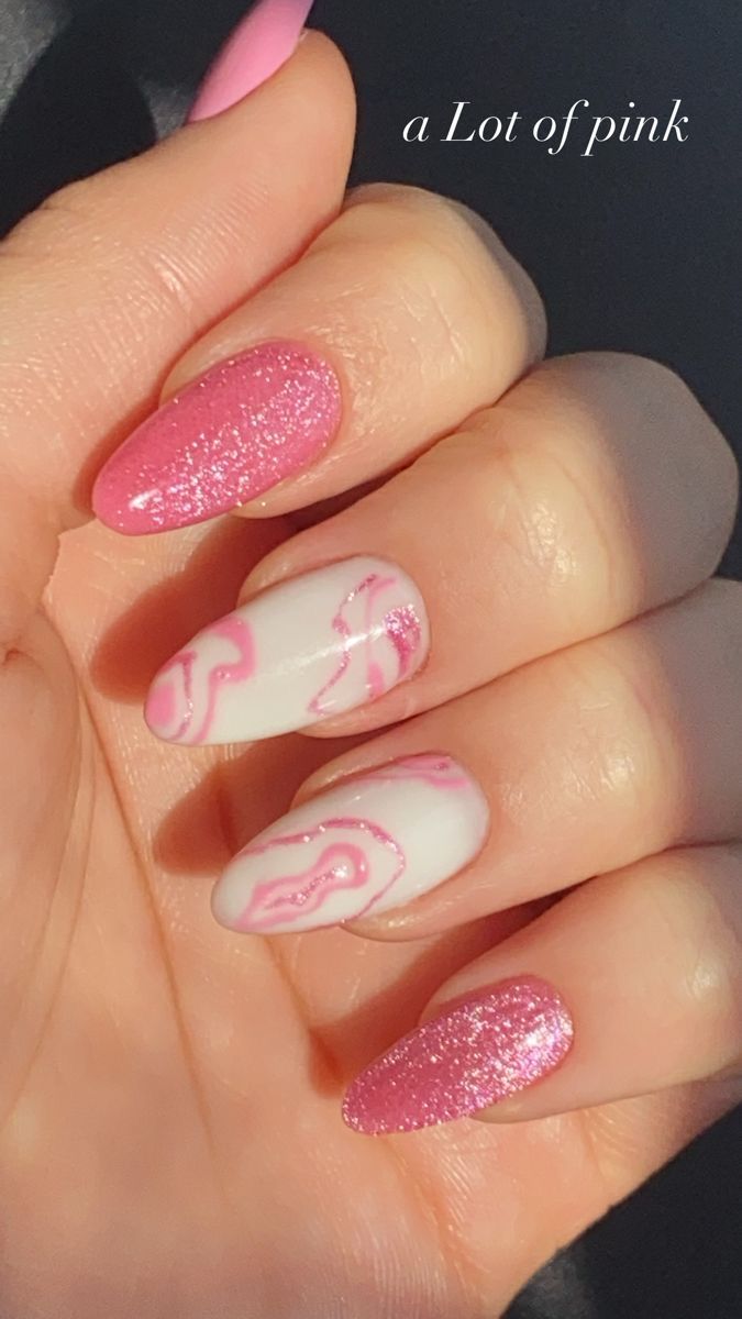Medium almond nails alternating between solid fuchsia pink glitter nails and white nails with pink swirl marble details, on a close-up hand shot