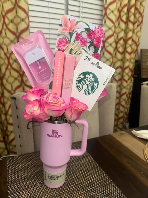 Pink Stanley Quencher tumbler filled with pink roses, Touchland hand sanitiser, Kayali perfume, and a Starbucks gift card arranged as a bouquet