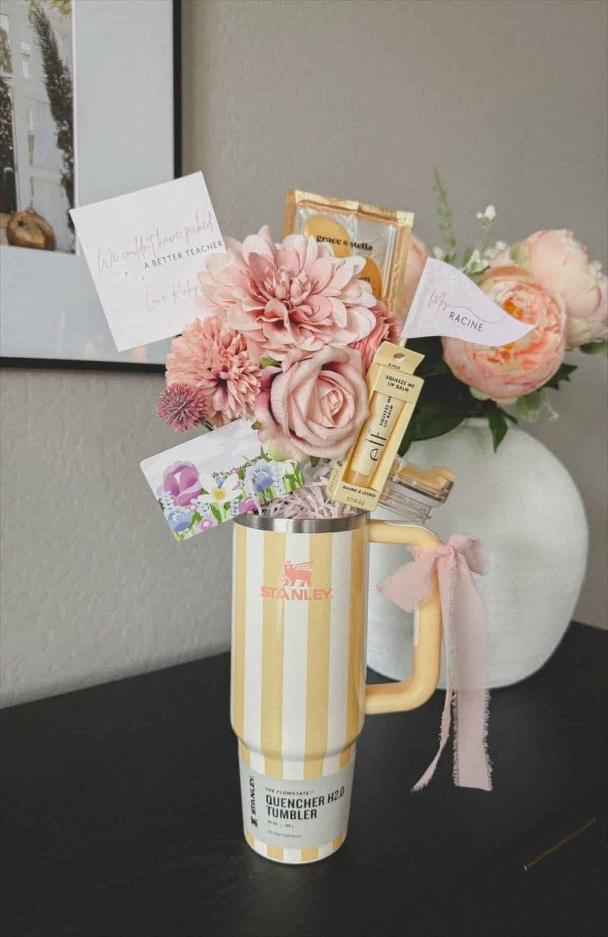 Yellow striped Stanley Quencher tumbler with pink linen bow filled with pink dahlias, roses, a personalised teacher card, e.l.f. lip balm, and a floral gift card