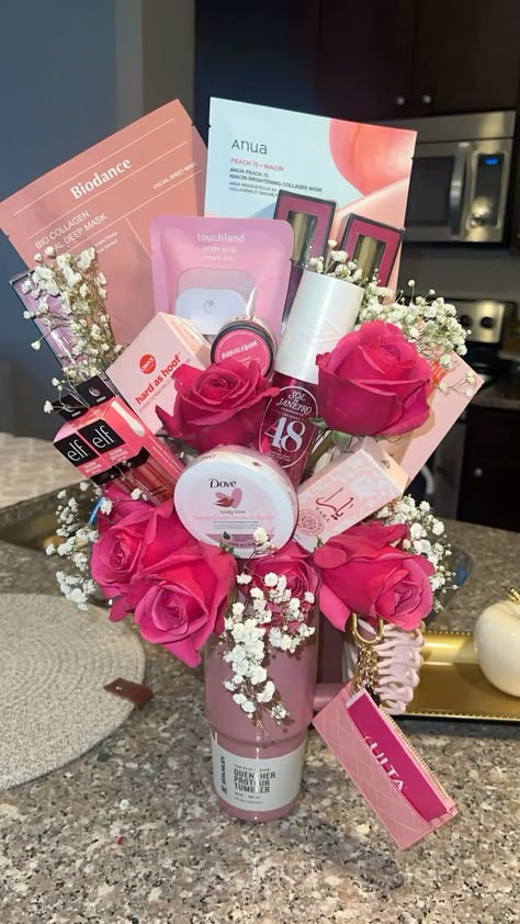 Pink Stanley Quencher tumbler filled with hot pink roses, baby's breath, Korean sheet masks from Biodance and Anua, Sol de Janeiro body cream, e.l.f. products, Dove cream, and an Ulta gift card
