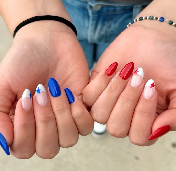 Two sets of medium almond nails held together, one hand with bold blue solid nails and a white star French tip accent, the other with bold red solid nails and a white star French tip accent.