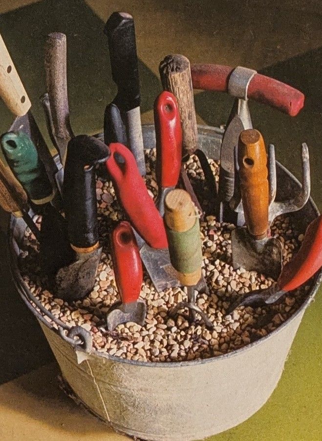Bucket filled with gravel holding upright garden hand tools