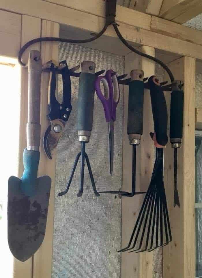 Old rake head mounted upside down as a hook for garden tools