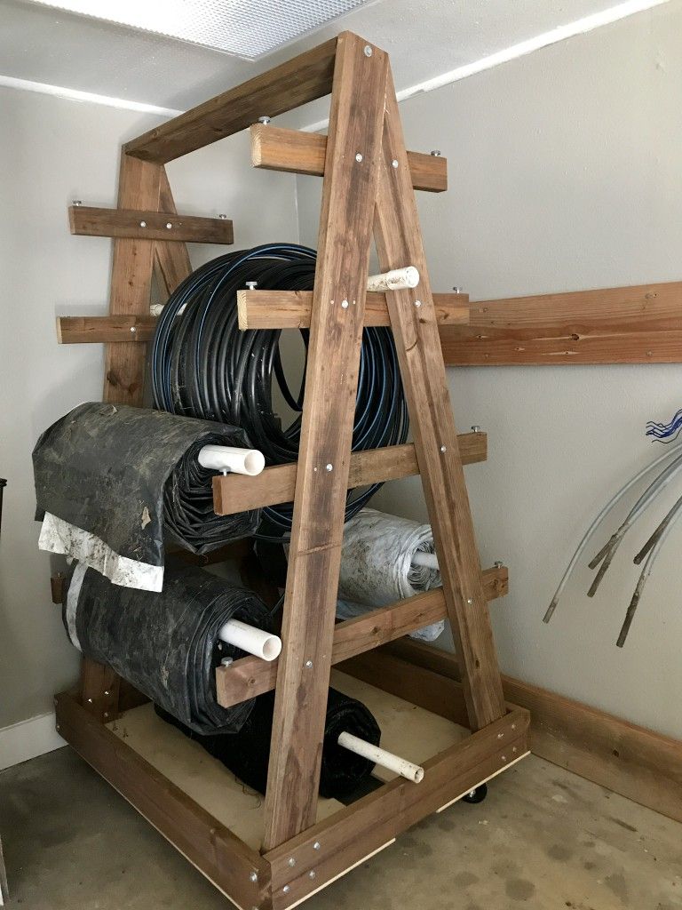 Rolling wood A frame rack storing hoses and tarps in a garage