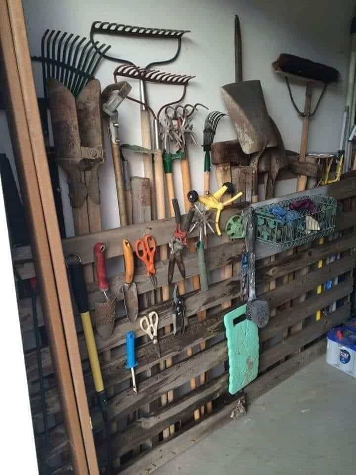 Pallet wall mounted with rakes, shovels, and hand tools