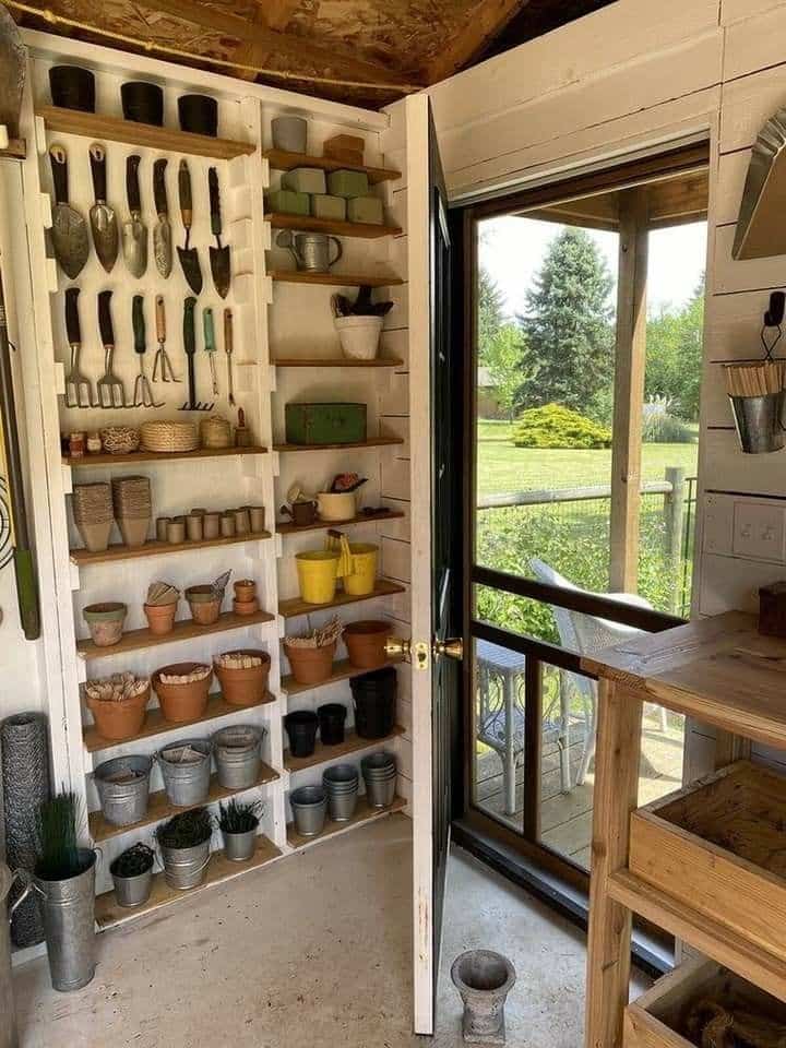 Wall of wood shelving holding pots, tools, and gardening supplies