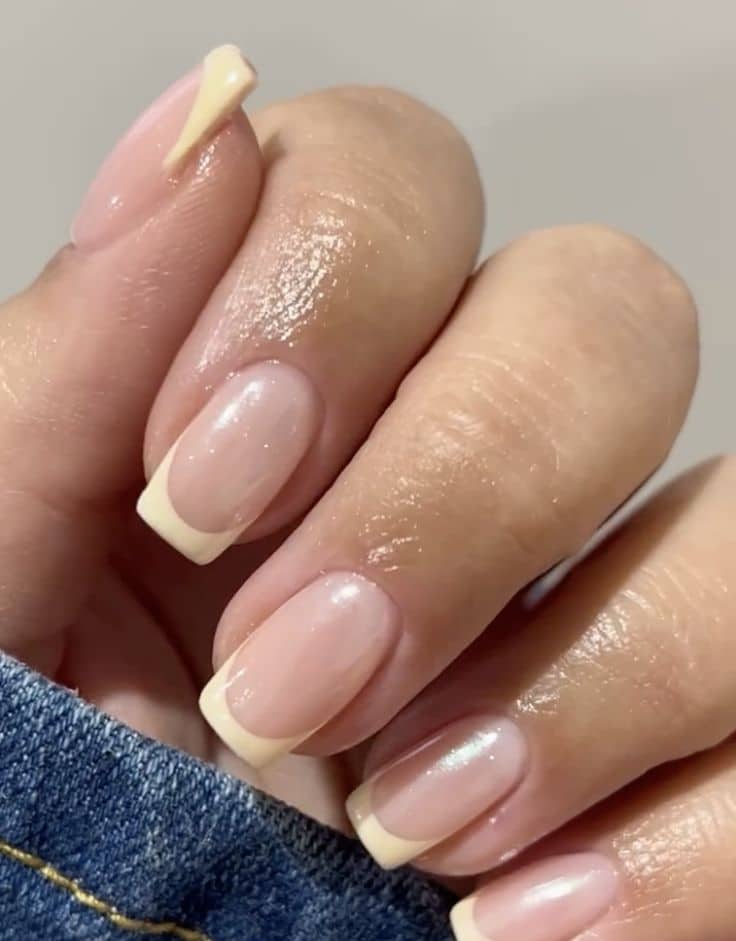 Square nails with a glazed natural base and soft pale yellow French tips.