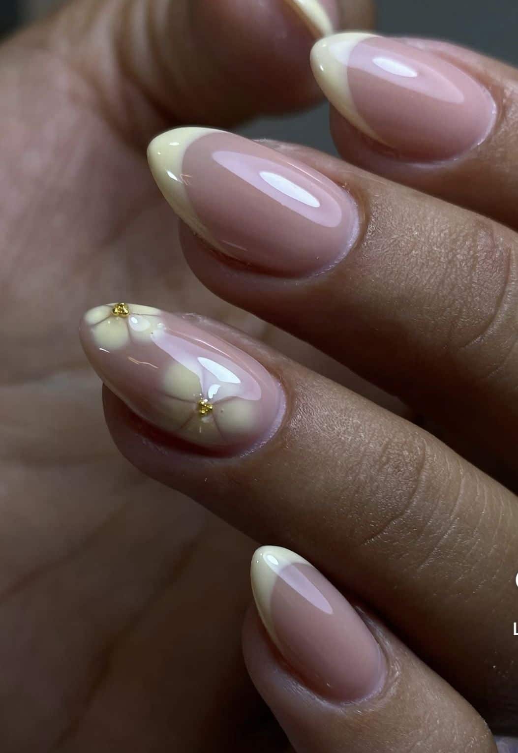 Almond nails with butter yellow French tips and a floral accent with gold beads.