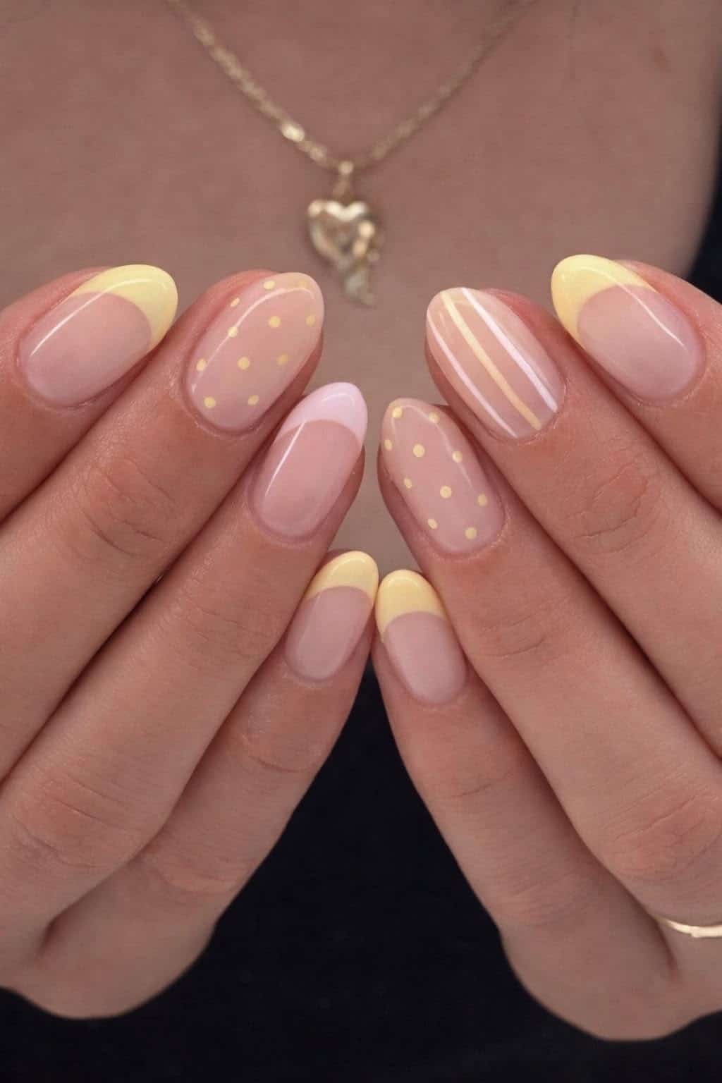 Almond nails mixing butter yellow dots, stripes and French tip designs across fingers.