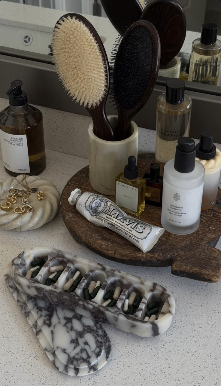 Wooden lazy susan stand with hair brushes in a stone cup, hand wash and hair products on a bathroom counter