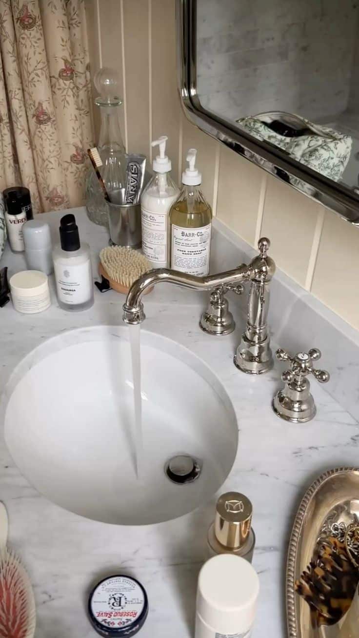 Vintage marble bathroom sink counter styled with matching soap dispensers, skincare and a scrubbing brush