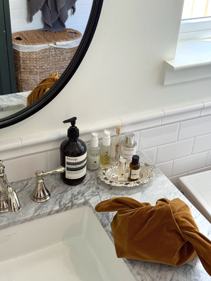 Marble bathroom counter with Aesop hand wash, skincare products and a small decorative tray